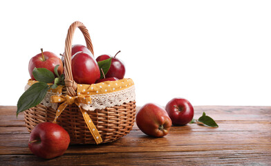 Ripe red apples in wicker basket on wooden table against white background. Space for text