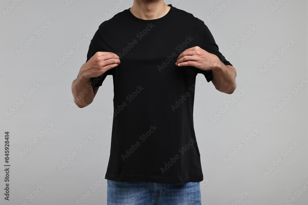 Wall mural Man in black t-shirt on grey background, closeup