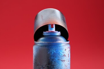 One can of bright spray paint with cap on red background, closeup
