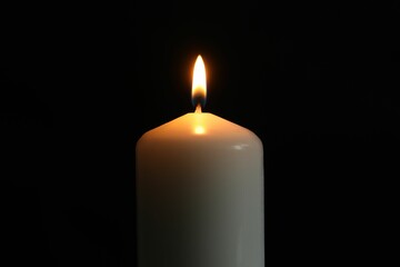 One burning church candle on black background, closeup