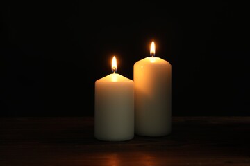 Two burning church candles on black background