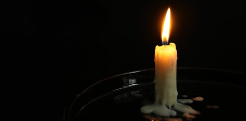 One burning church candle on black background, space for text