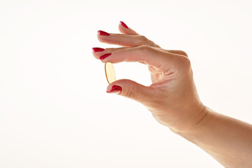 Woman holding an omega 3 capsule on a bright background