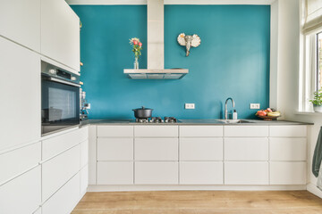 Modern kitchen with vibrant teal accent wall and white cabinetry