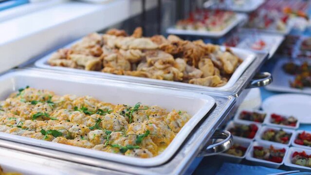 Beautifully decorated catering banquet table with different main course hot food dishes and garnish, with rice, chicken, salmon fish, lamb, vegetables and kebab on party event wedding celebration
