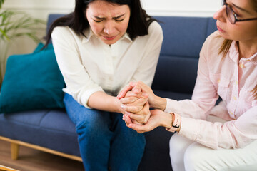 Closeup of a female psychologist holding a woman's hands during a therapy session showing support