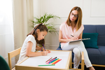 Child psychologist focused on observing a young girl in therapy to enhance her well-being through understanding and improvement