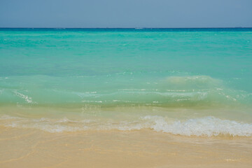 Waves and foam on a tropical sandy beach.