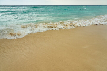 Waves and foam on a tropical sandy beach.