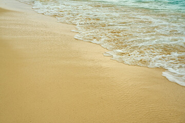 Waves and foam on a tropical sandy beach.