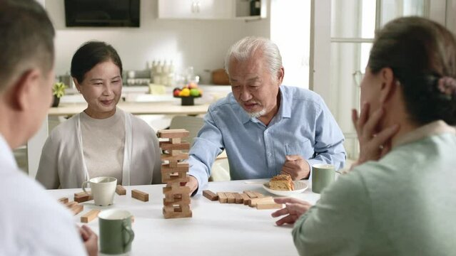 group of four asian senior people two couples gathering together at home playing with building blocks