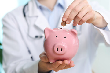 Doctor with piggy bank in hospital, closeup