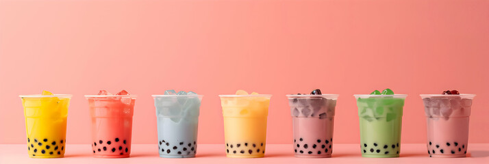 A lineup of colorful bubble tea drinks in transparent cups against a soft pink background, showcasing a variety of flavors.