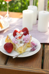 Piece of delicious homemade cake decorated with fresh strawberries and candles on table outdoors, closeup