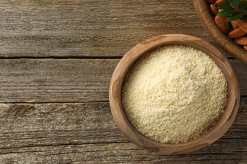 Fresh almond flour, branch and nuts on wooden table, flat lay. Space for text