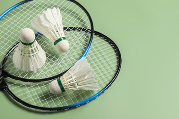 Feather badminton shuttlecocks and rackets on green background, above view. Space for text