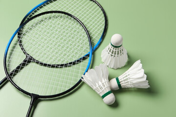 Feather badminton shuttlecocks and rackets on green background, above view