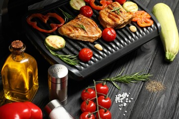 Electric grill with different products on black wooden table