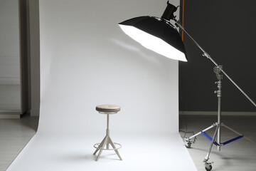 White photo background, stool and professional lighting equipment in modern studio
