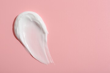 Sample of face cream on pink background, top view. Space for text