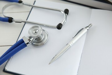 One new medical stethoscope on white wooden table, closeup
