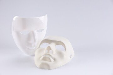 Plastic face masks on white background, space for text. Theatrical performance