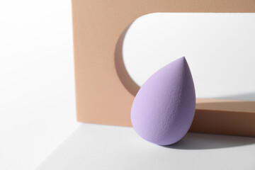 Stylish presentation of violet makeup sponge on white background, space for text