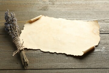 Sheet of old parchment paper and lavender flowers on wooden table