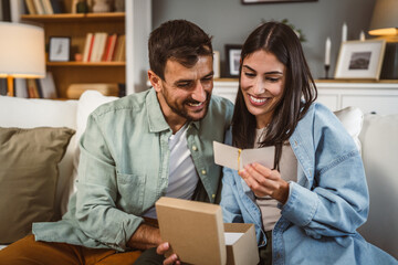 Girlfriend and boyfriend read birthday card greetings together at home