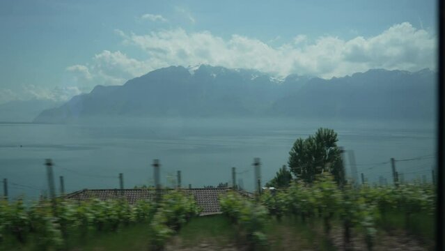 Scenic Swiss Train Ride - Typical Buildings, Verdant Fields, Majestic Lake, Surrounded by Grand Alps Through Window View