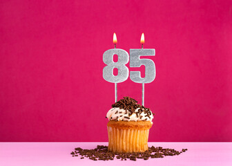 Birthday celebration with candle number 85 - Chocolate cupcake on pink background