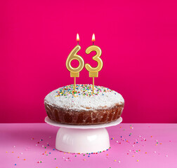 Lighted birthday candle number 63 - Birthday card on pink background
