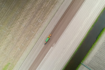 Aerial view of farm equipment seeding in the empty agriculture fields in The Netherlands.