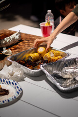 BBQ family gathering, one hand pick up corn