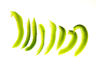 A close up of green fresh peppers. The peppers are sliced and arranged in a row on white background. Food preparation concept. Nature colors.