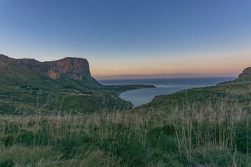 Colorful twilight after sunset over rock formation of Monte Monaco with view at the coast of the mediterranean sea, San Vito lo Capo, Sicily, Italy