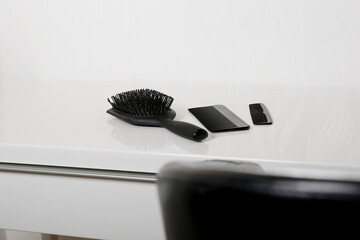 Close up of used black hair brush and combs with some hair on white table, head skin hygiene concept