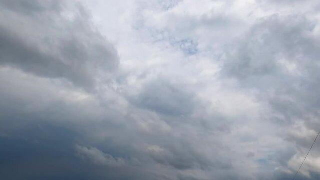 Huge grey clouds gather in atmosphere. Low angle view on the dramatic rainy cloudscape spreading by the sky. Timelapse.