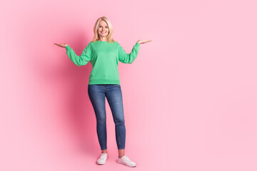 Full body photo of nice pensioner woman compare hold empty space wear trendy green outfit isolated on pink color background © deagreez