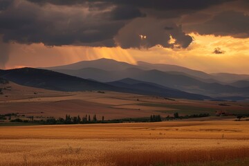 Fototapeta premium A stunning sunset over rolling hills and fields, with dramatic clouds and rays of sunlight piercing through. The landscape is bathed in golden light