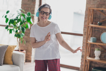 Photo of pretty retired woman earphones dance wear white outfit home flat rest relax spend free...