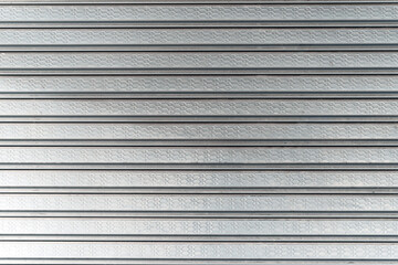 Obraz premium Abstract image of a corrugated metal roller shutter door with a shiny texture.