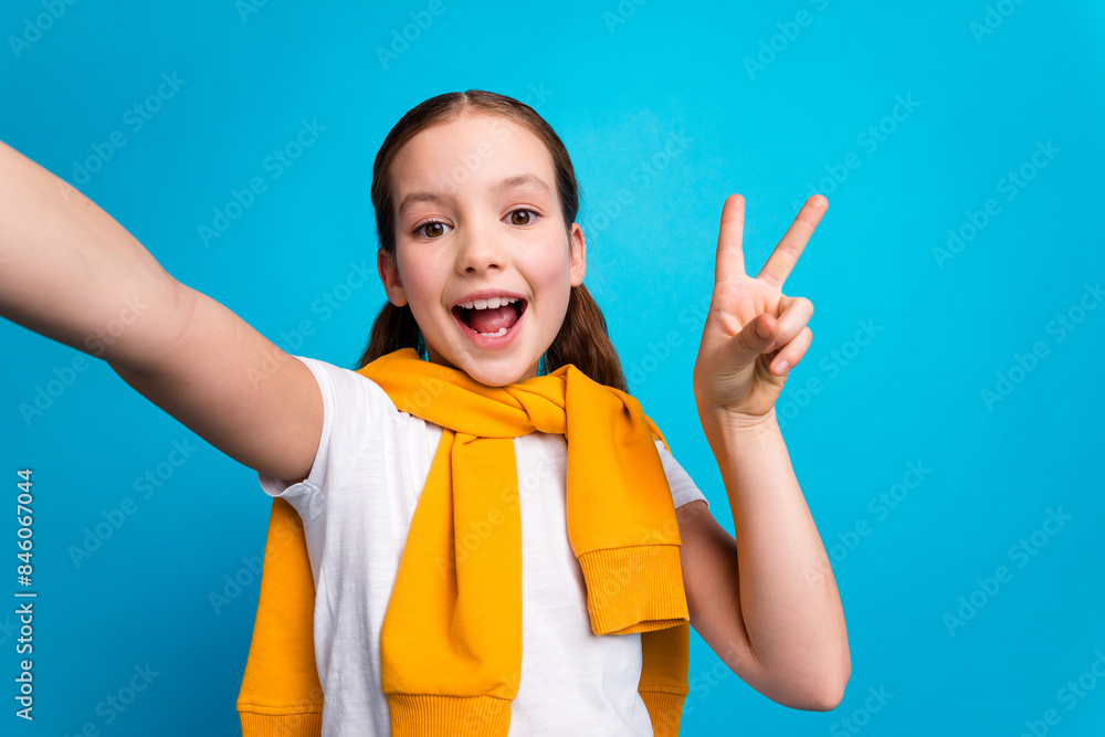 Canvas Prints Photo of sweet lovely small girl wear tied pullover recording video showing v-sign empty space isolated blue color background