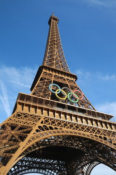Vue en contre-plong&eacute;e sur la tour Eiffel d&eacute;cor&eacute;e avec les anneaux olympiques, c&eacute;l&egrave;bre logo symbole des jeux olympiques, pour les JO d&rsquo;&eacute;t&eacute; de Paris 2024 &ndash; juin 2024 (France)
