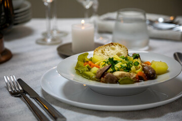 Luxurious table setting with white plates, crystal glasses and fine cutlery. Soup