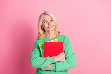 Photo portrait of lovely senior lady look empty space hold copybooks dressed stylish green garment isolated on pink color background