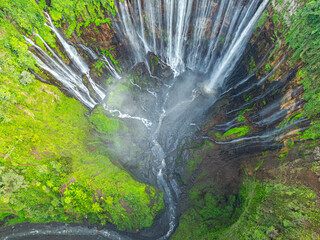 .Aerial view Tumpak Sewu Waterfall The most beautiful in Indonesia..The hills and mountains in Java are full of amazing waterfalls..Thousands of waterfalls flow together at Tumpak Sewu. green forest..
