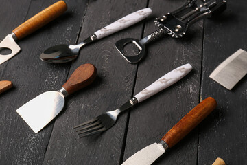 Different kitchen utensils on black wooden background