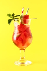 Glass of fresh watermelon lemonade with lime and mint on yellow background