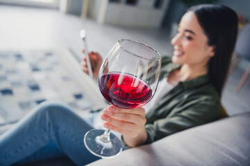 Photo of pretty young lady use phone hold show wine glass wear green shirt weekend modern apartment indoors